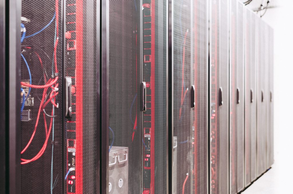 Rows of enclosed server cabinets with red and blue cabling in a data center