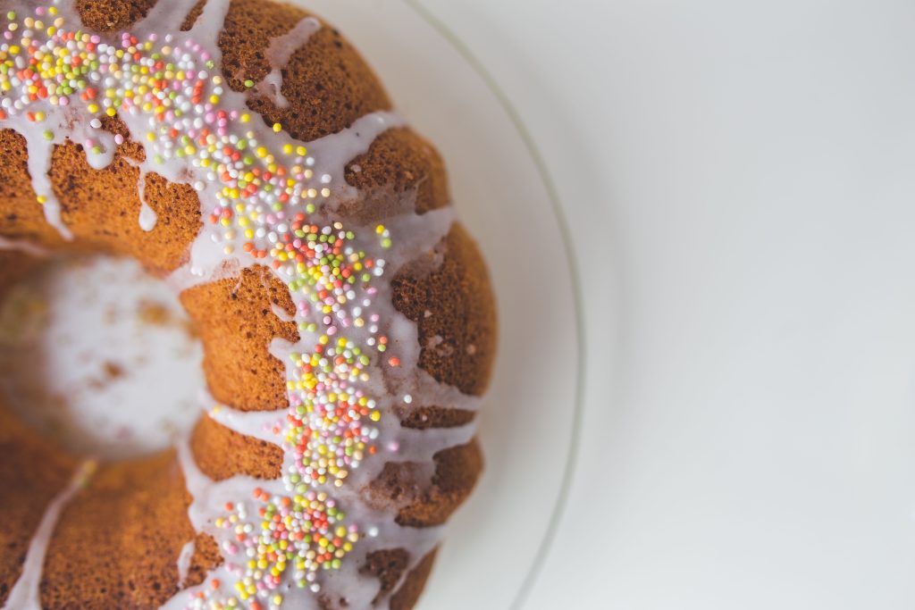 A bundt cake topped with white icing and colorful sprinkles