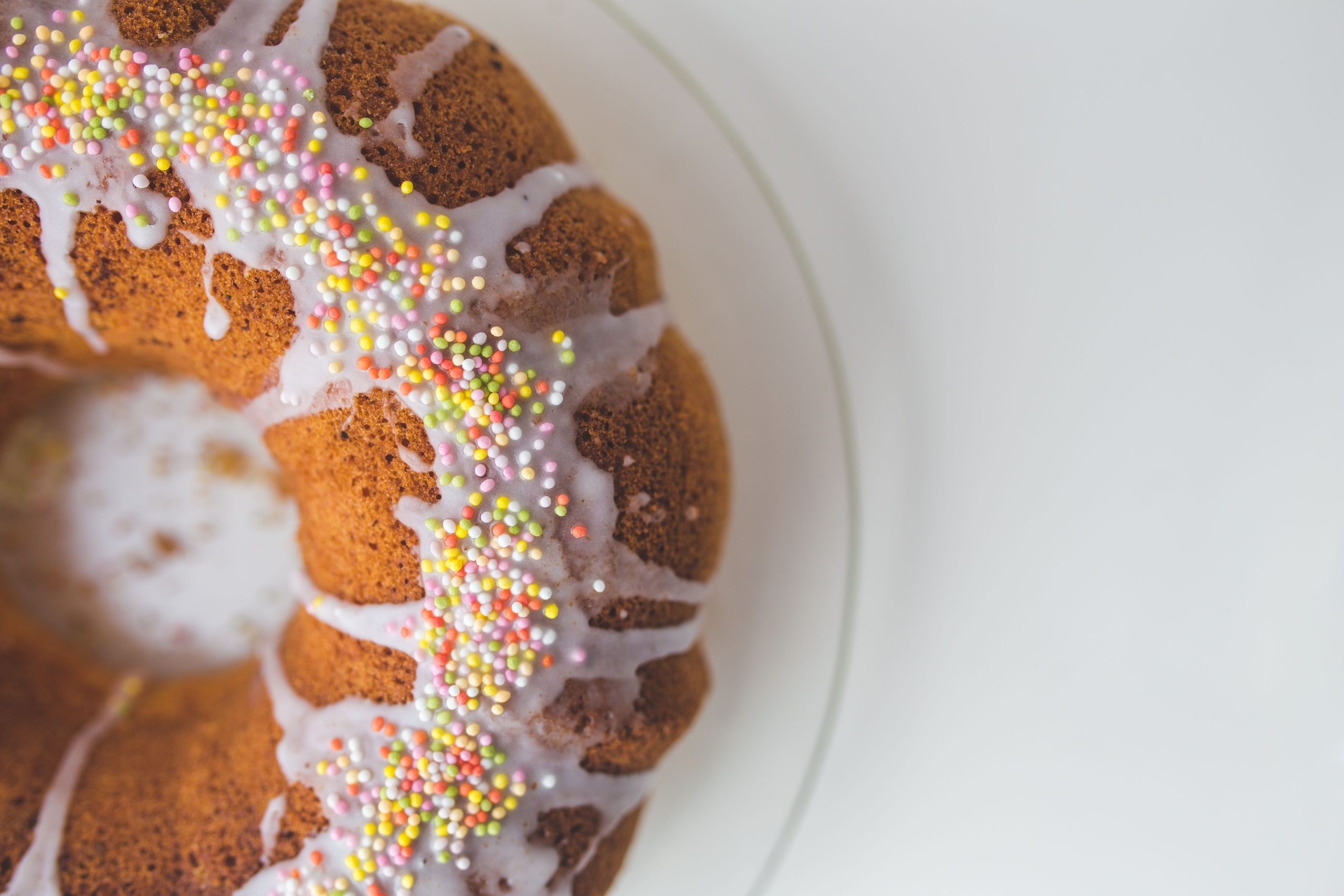 A bundt cake topped with white icing and colorful sprinkles