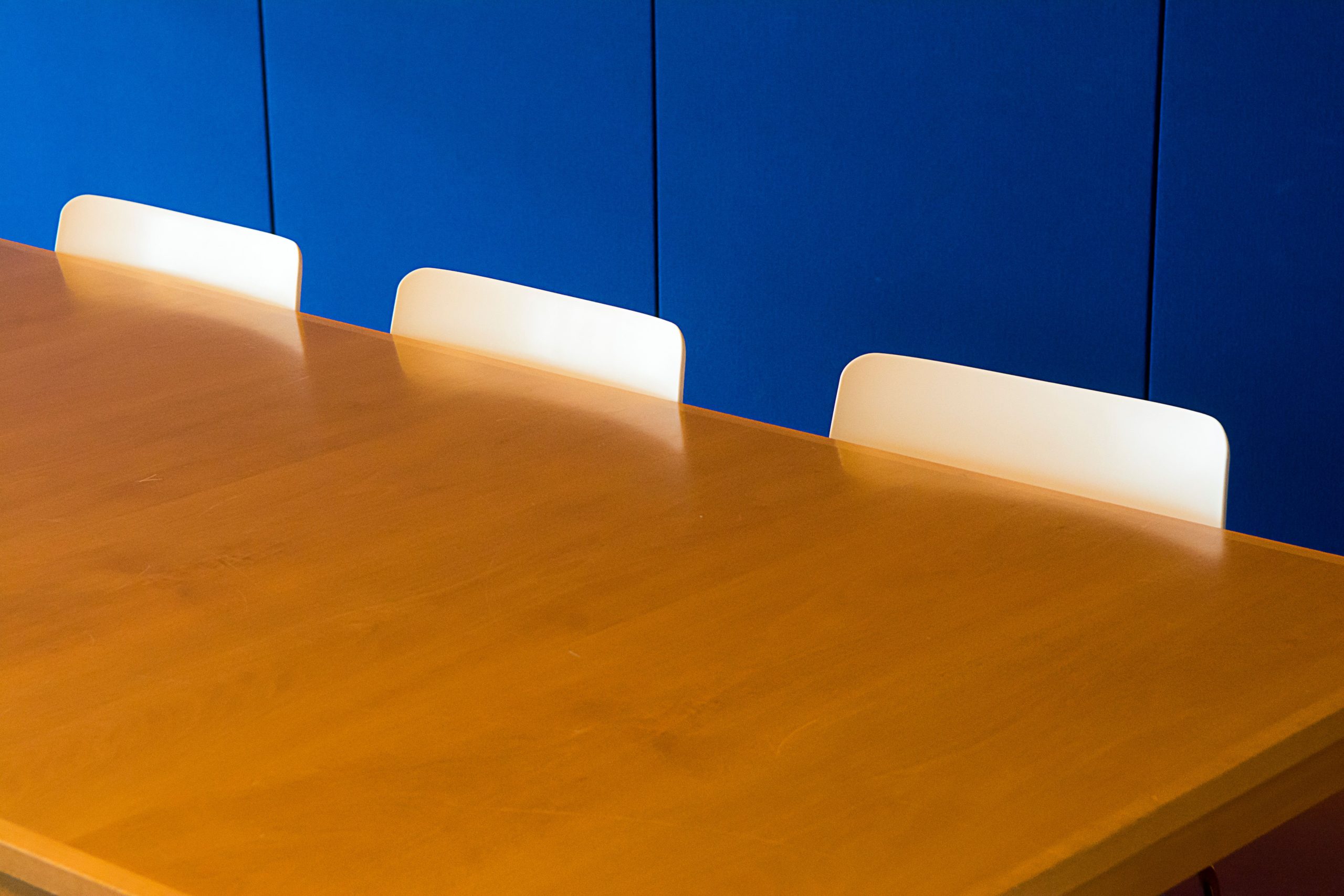 White chairs beside a wooden conference table against a blue wall