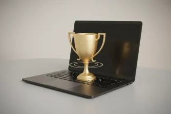 Laptop on a clean desk projecting a glowing golden trophy, symbolizing remote employee recognition.