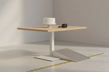 Adjustable-height cake table with nearby ramp and tactile floor path, plus noise-canceling headphones, in a minimal venue.