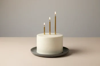 Minimal white cake with three gold candles forming a rising bar chart on a neutral background.